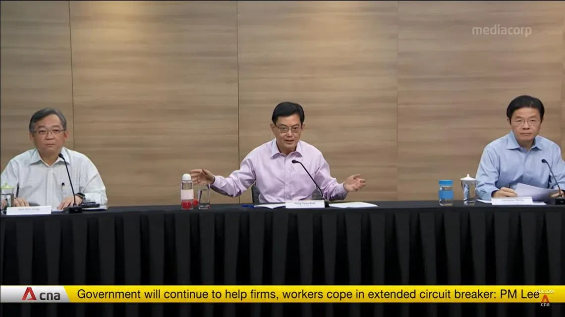 副总理兼财政部长王瑞杰主持今天的跨部门抗疫工作小组记者会，与旁边的部长都坐在安全距离之外。（记者会视频截图）