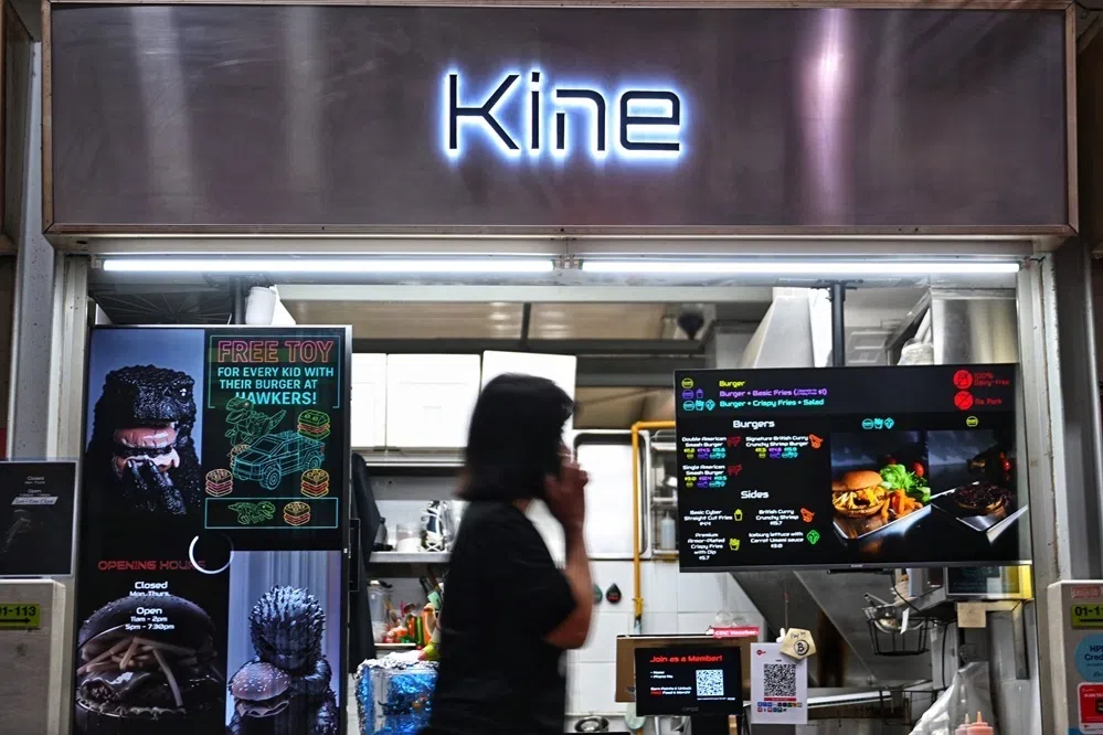 位于ABC砖厂熟食中心的Kine，金属招牌上只镶上摊位的名字，菜单则投放在荧幕上。38岁的摊主Chen Yi Wei说，有顾客告诉他，这是他见过最酷炫的小贩招牌。