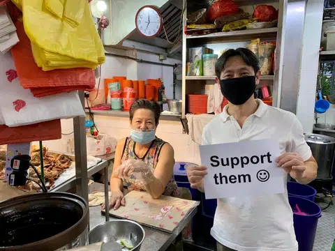 义顺集选区议员黄国光2020年6月拿着一张写着“支持他们”（Support Them）和画有笑脸的纸张，到小贩中心呼吁公众支持小贩。（黄国光面簿）