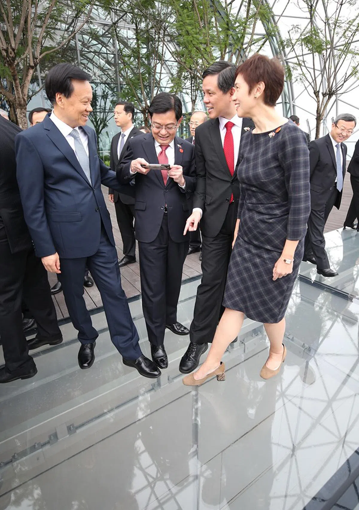  王瑞杰（左二）为陈敏尔（左一）、陈振声（右二）和杨莉明（右一）的鞋子拍了张“合照”。其实是在拍玻璃地板下的风景。（王瑞杰面簿） 