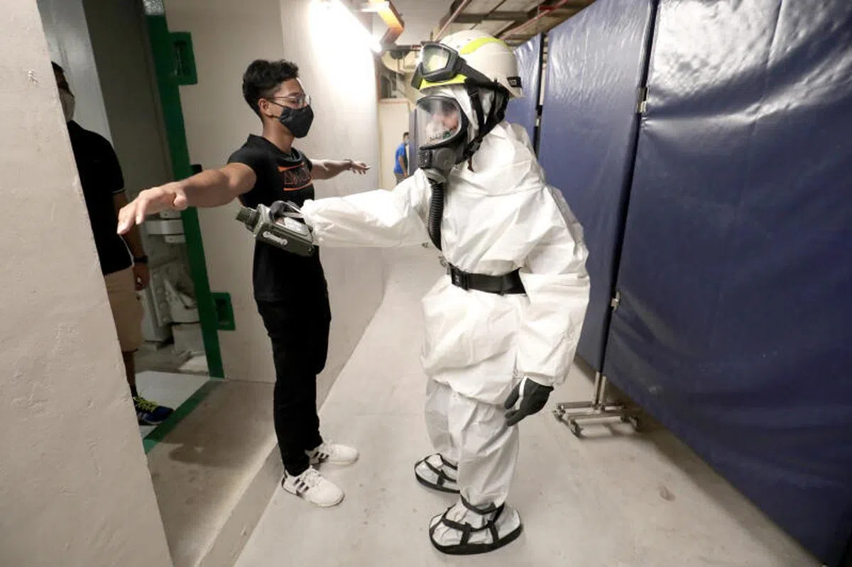 民防的公公共防空壕与韧性人员会确保避难者身上没有沾染危险物质，才可入内。（联合早报）