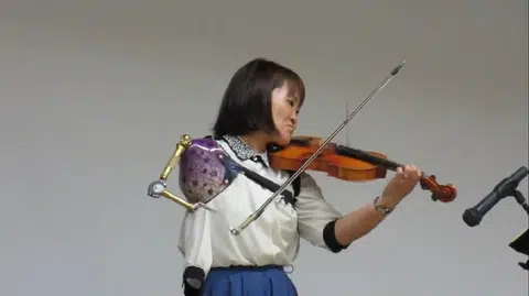 在日本举行的一场“永远不会放弃”的小提琴演奏分享会上，33岁的伊藤真波完美地用义肢在小提琴上奏出中岛美雪的著名歌曲《线》。（视频截图）
