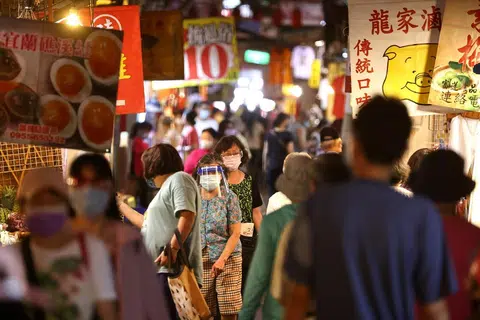 台湾冠病疫情逐渐缓和，民众在台北的一个夜市里戴着口罩逛街。（路透社）