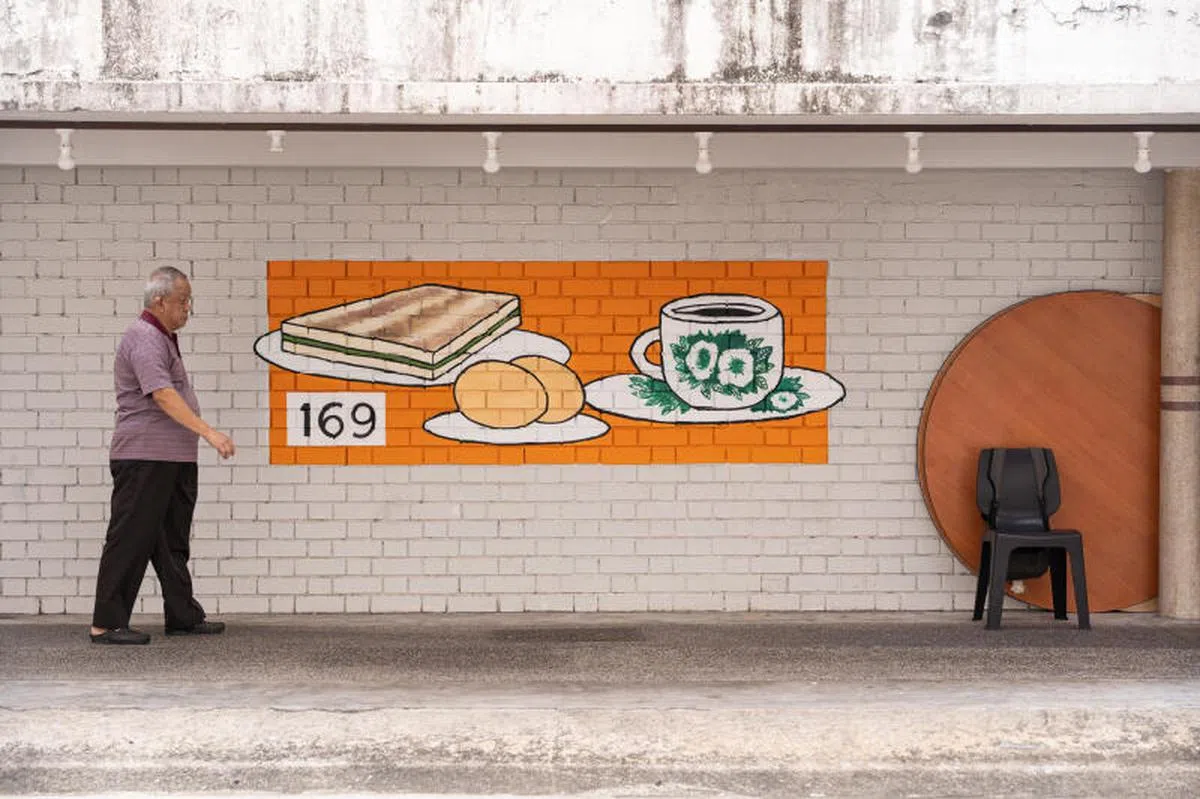 女皇镇史德林路的组屋区内新绘制了11幅壁画，协助年长及患有失智症的居民寻找他们回家的路。图为底层有咖啡店的第169座组屋外墙，绘制了年长者熟悉的咖啡、咖椰吐司和半熟蛋的传统早餐。（联合早报）