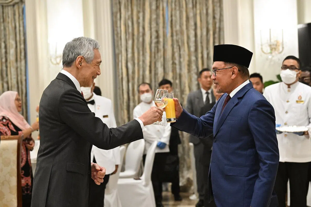 李显龙总理（左）与马国首相安华（右）举杯言欢。（海峡时报）