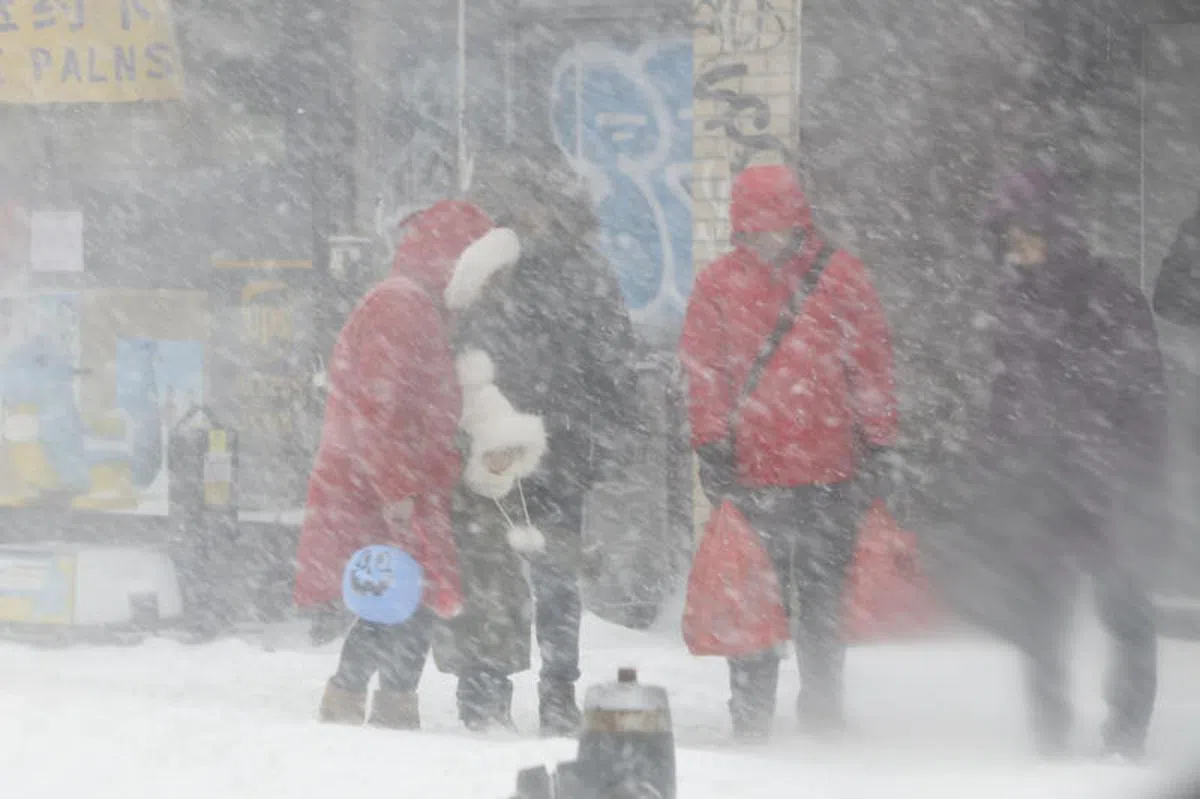  暴雪中纽约法拉盛街区的行人。（中新社） 