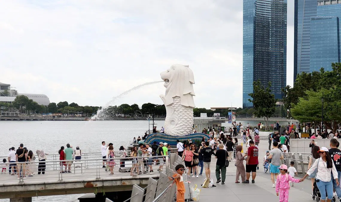 游客访新加坡旅游景点鱼尾狮公园时拍照留念。（联合早报）