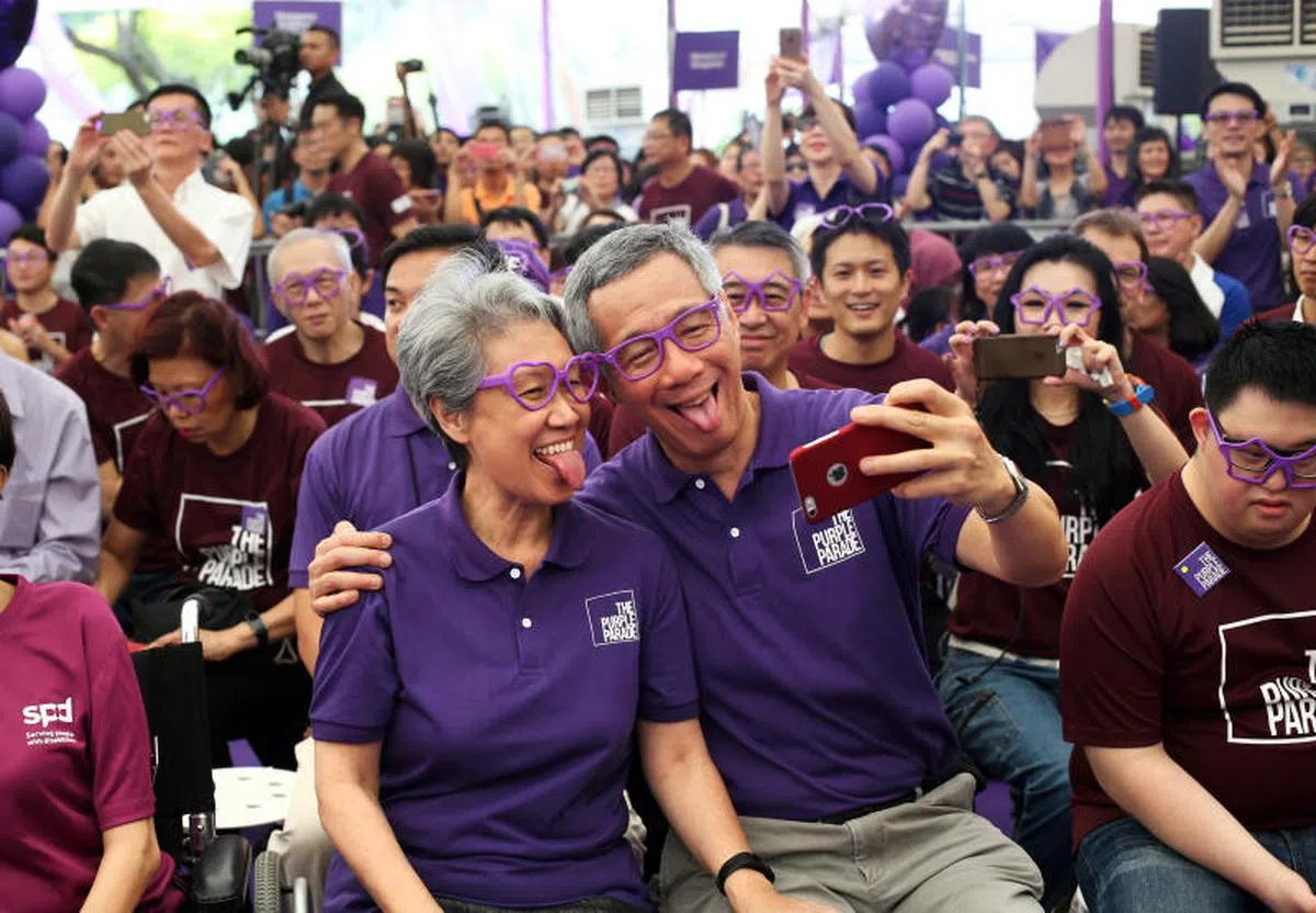  2015年，李显龙总理与夫人何晶参加“紫色行动”时与现场公众一同戴上紫色镜框，两人还用手机调皮合照。（联合早报） 