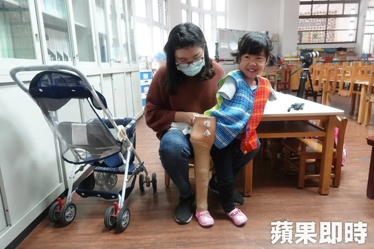  虽然穿上义肢时辛苦，又立一想到待会儿要和朋友玩耍，就会笑得合不拢嘴。（苹果日报 台湾） 