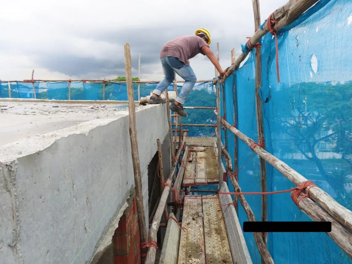 一名建筑工人在没有系上安全带的情况下正从屋顶跳下鹰架，这项危险行为可能导致他被绊倒，甚至从高处摔下。（人力部）