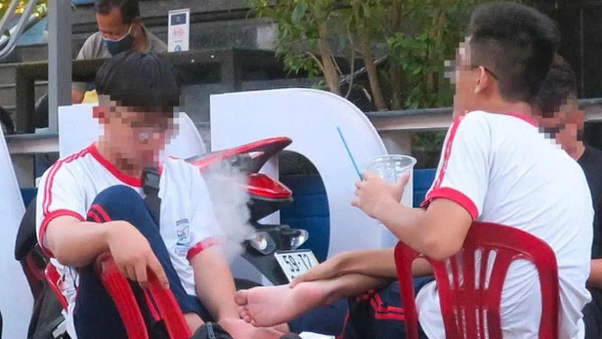 根据越南法律，年龄未满18岁者不能购买香烟，但越南目前没有任何管制电子烟的条例。图为越南学生吸电子烟。（互联网）
