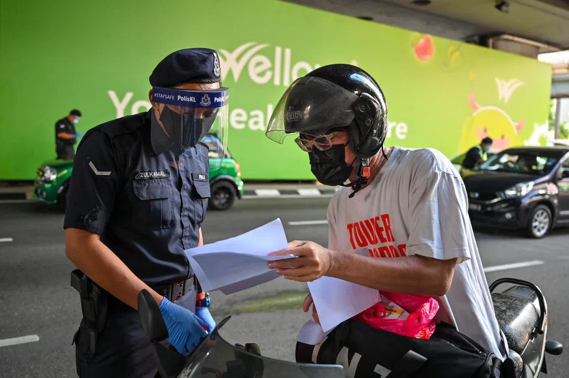 一名马国警员正在检查民众的通行文件。（法新社）