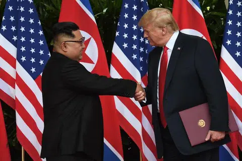 特朗普（右）与金正恩签署联合文件之后，微笑握手。老特这个时候似乎使出的“握手杀”，将小金拉向自己。