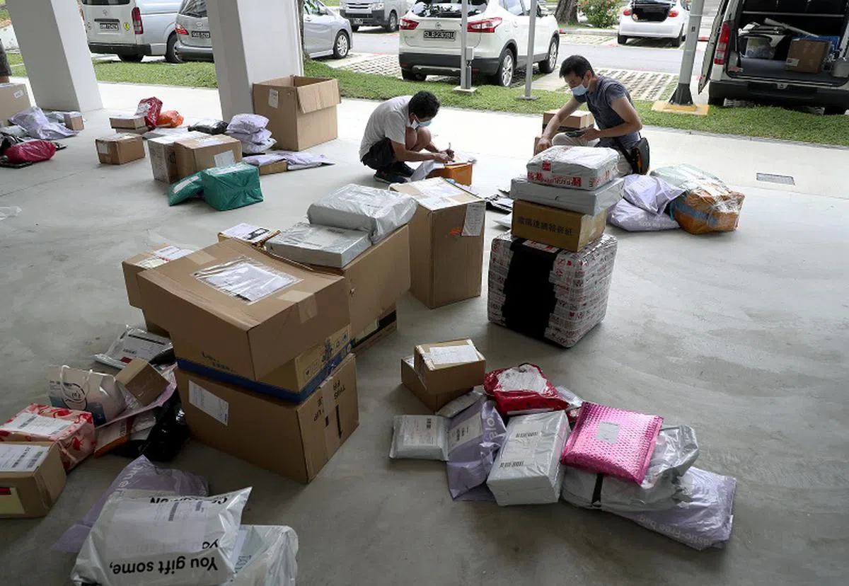  有些包裹送货员先在组屋楼下为包裹分类，然后再上楼派送。（联合早报） 