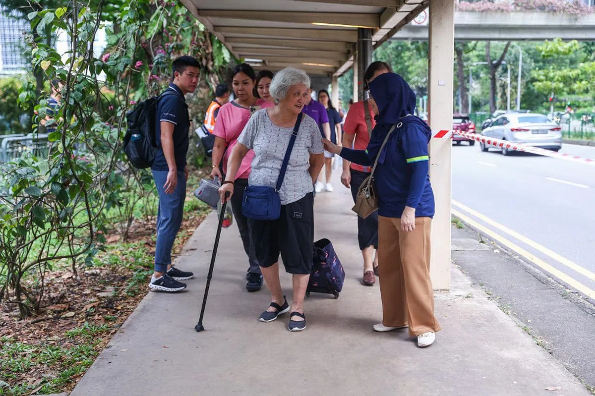 裕廊东地铁站外，一位戴着头巾的妇女向一名拄着拐杖的年长妇人表示慰问。（联合早报）