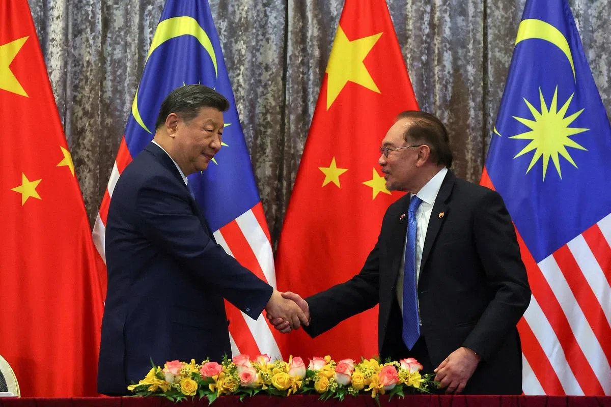 习近平（左）官访马国，但当地华文报的一项疏失，一定程度上模糊了这场外交大戏的焦点。右侧为马国首相安华。（路透社）