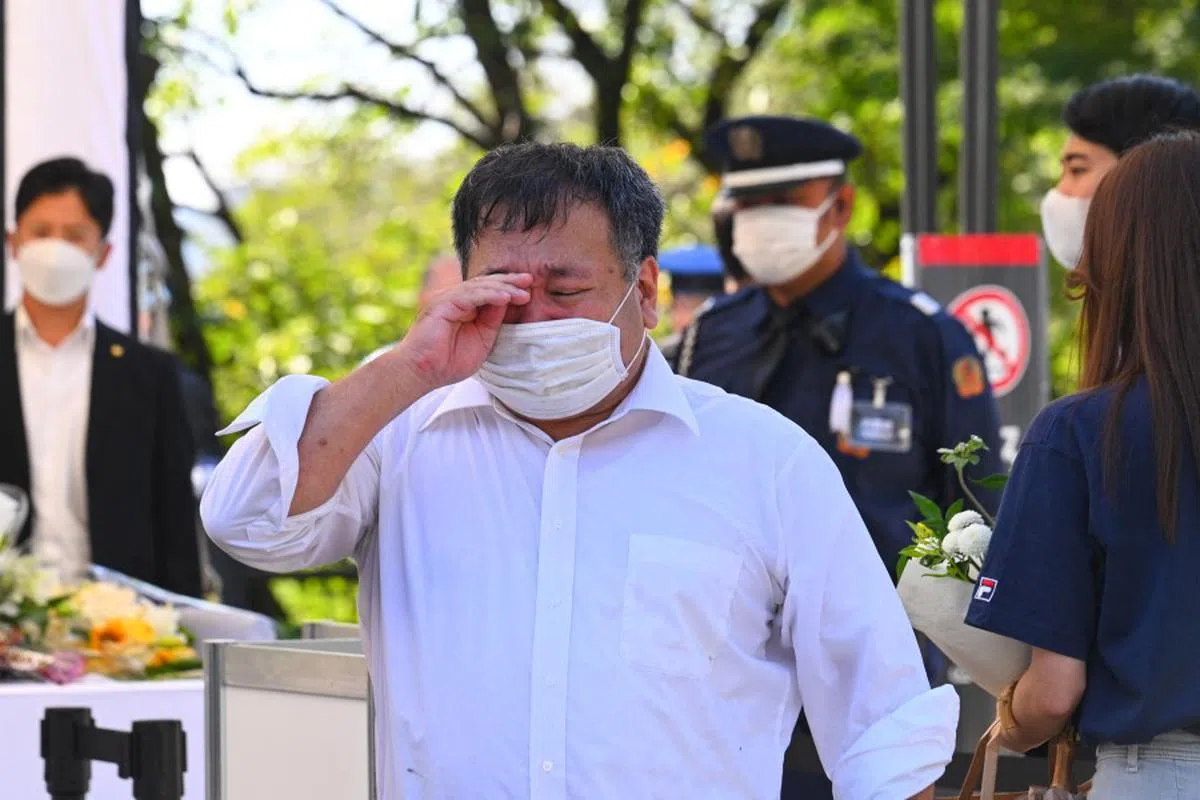 一名男子在武道馆外的献花台上献花悼念案背后，忍不住流下眼泪。（法新社）