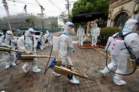4月14日，全副武装的义工走入上海黄浦区的一个住宅区消毒。（路透社）