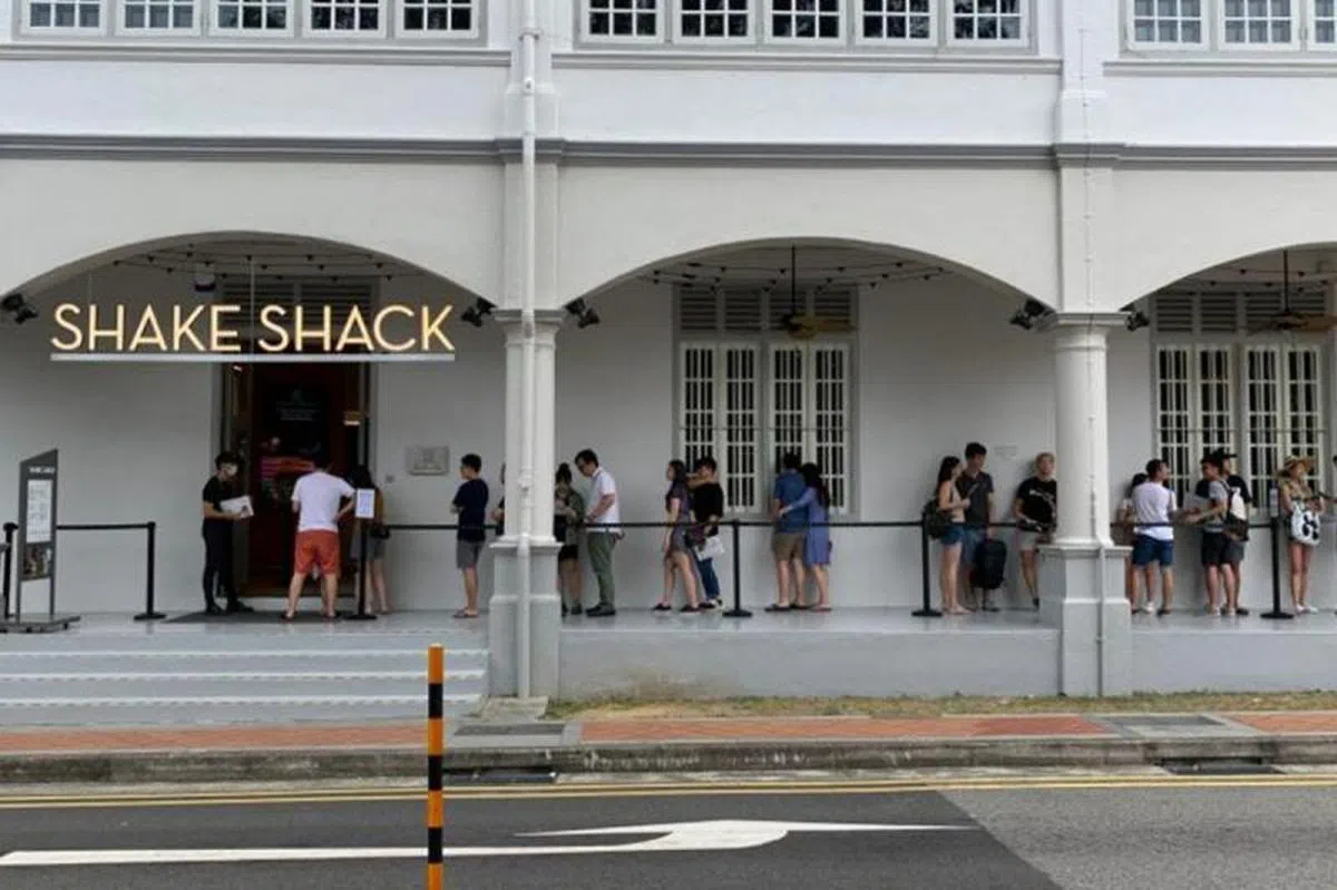  食客在位于尼路（Neil Road）的Shake Shack 排队时也自主与前后批食客隔开一段距离。（海峡时报） 