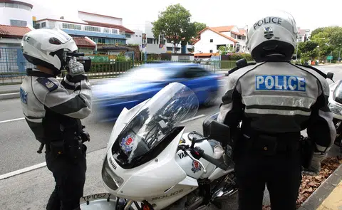 交通警察日前在淡马锡中学外展开取缔行动，使用激光测速器取缔超速驾车者。（联合早报）