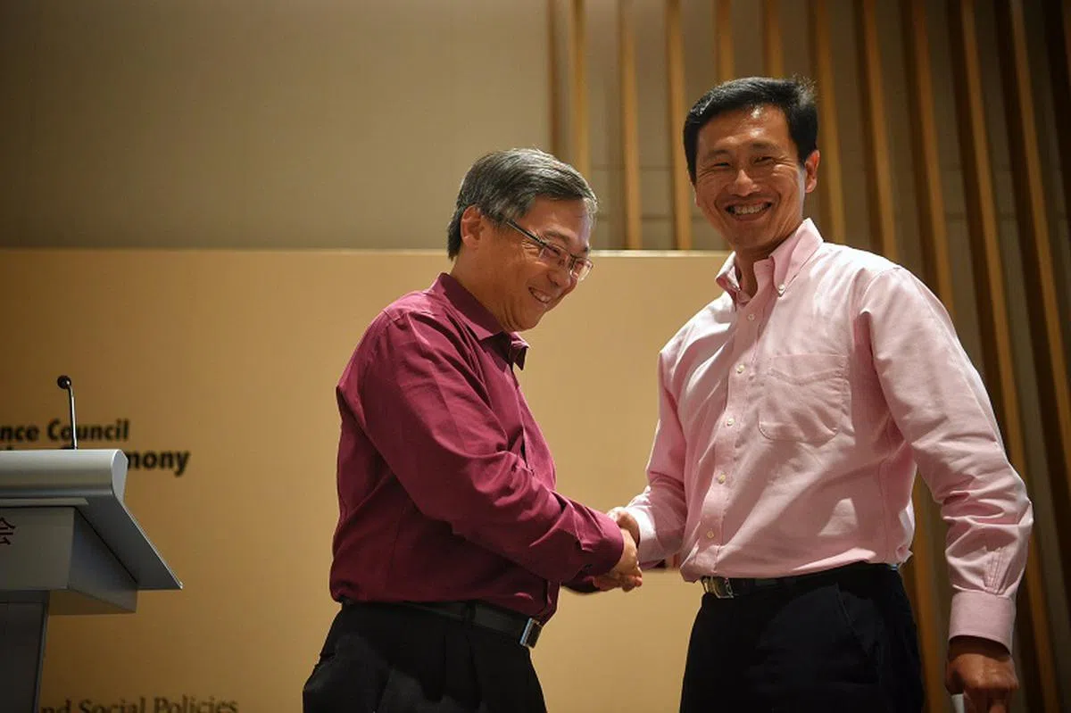  精通双语的王乙康（右）去年7月，从卫生部长颜金勇手中接过领导棒子，正式出任华社自助理事会董事会主席。（海峡时报） 