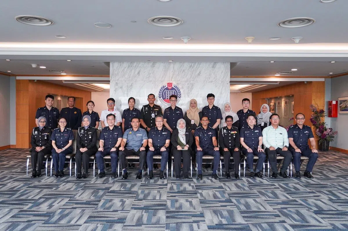 新马两地移民局官员合照——人多担心不够吃，所以一次送上两个蛋糕？（新加坡移民局）