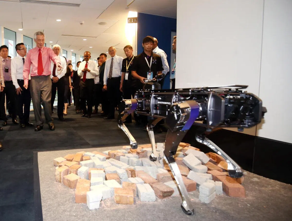 李显龙总理（粉红衣者）2019年向内政科技局人员了解四脚机器人Rover-X的运作。（联合早报）