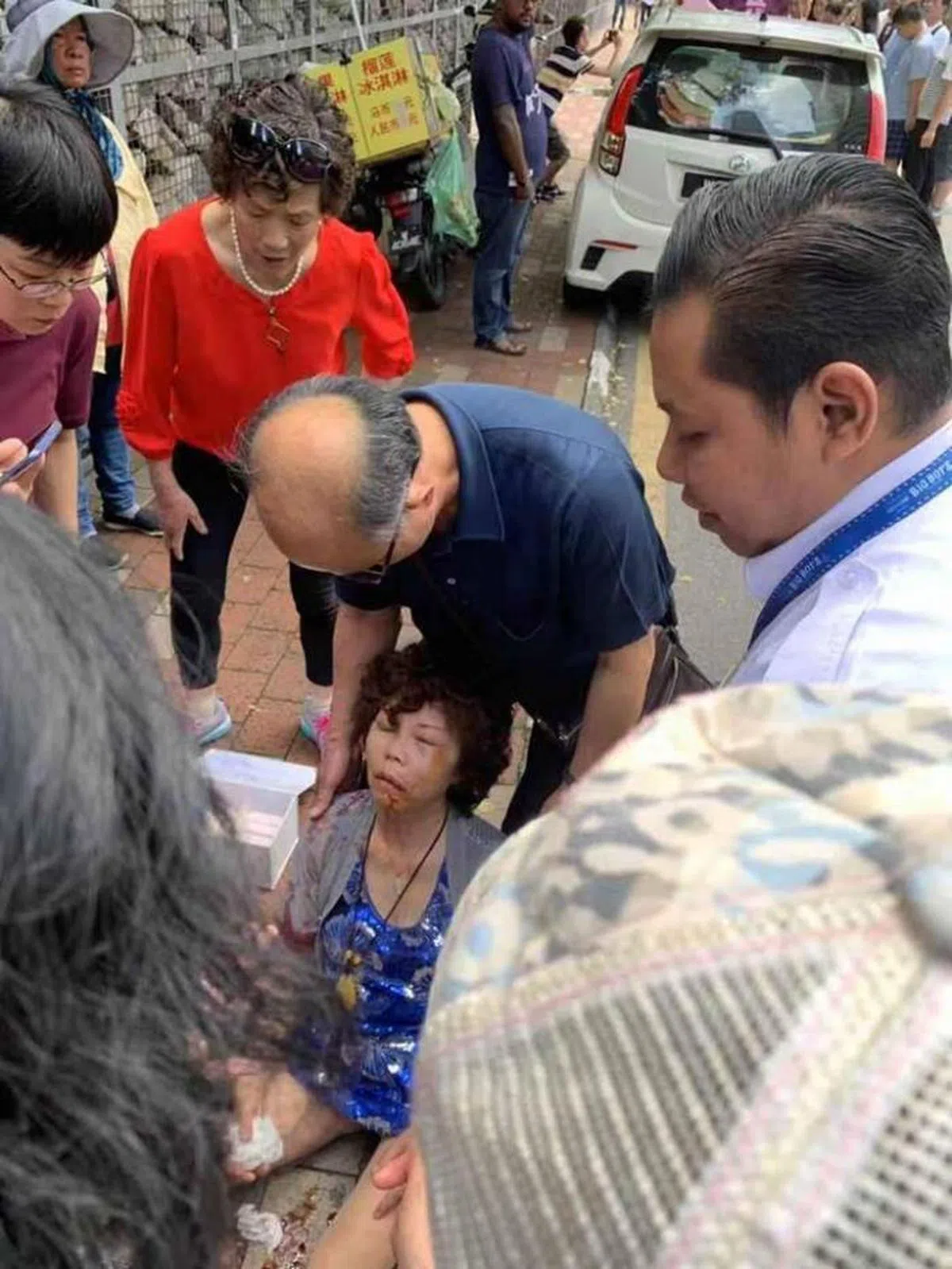  中国游客陈月珍浑身是伤坐在人行道上，看上去好像不省人事。（中国报） 