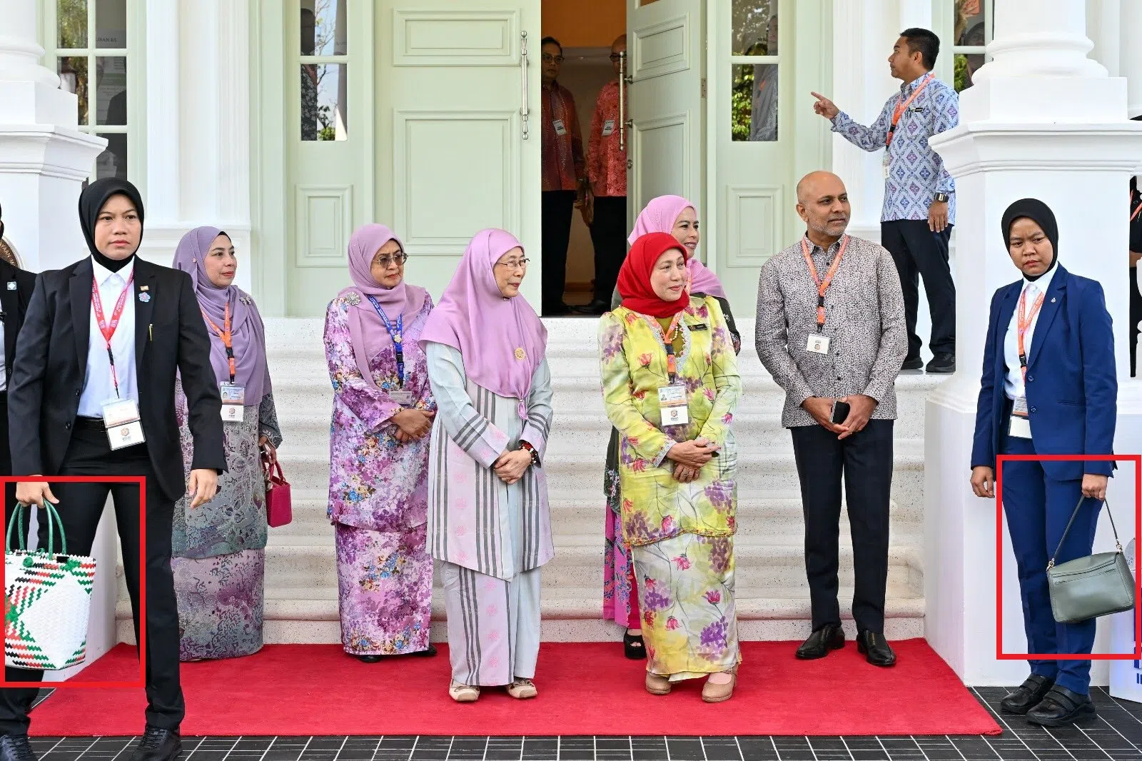 图中可见两位女保镖疑似协助某位夫人或高官拎包。