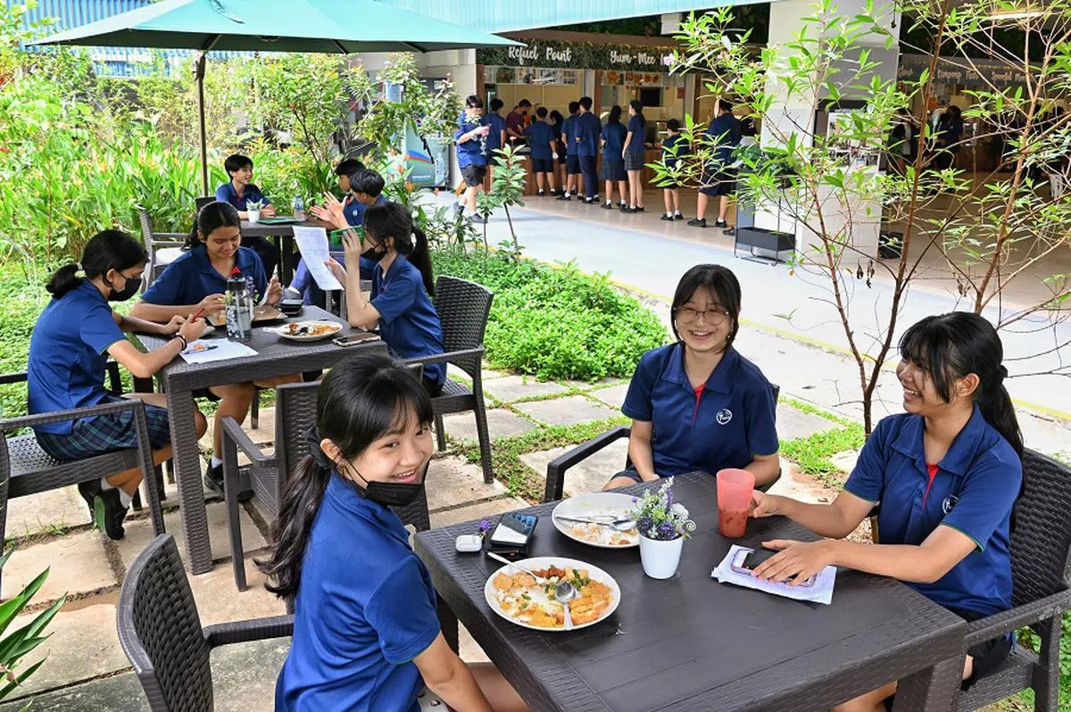 裕华中学的学生在绿色的遮阳伞下，到户外用餐。（海峡时报）