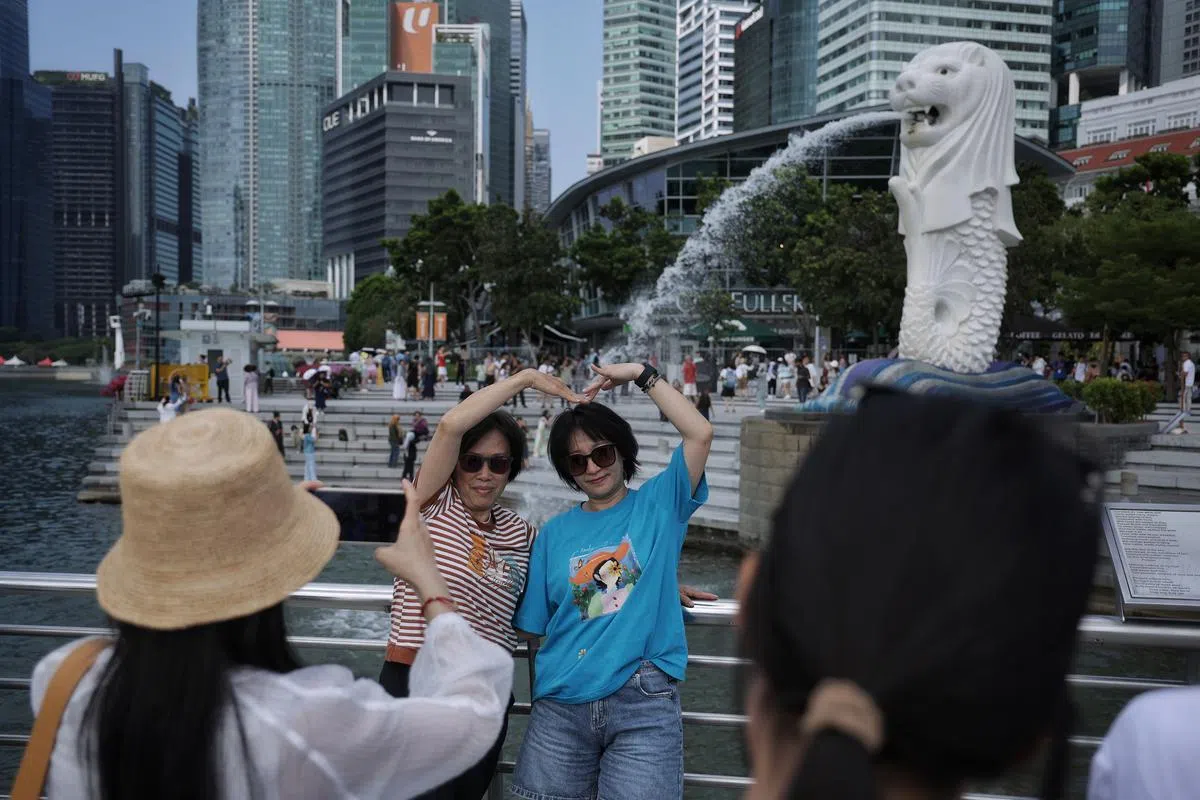 旅客在鱼尾狮公园拍照打卡留念。（海峡时报）