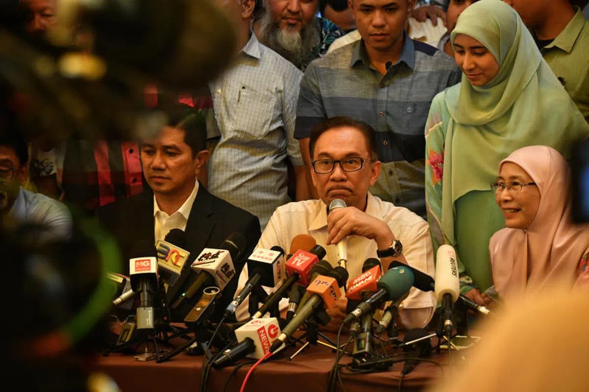  安华（中）重获自由之后，昨天在住家召开记者会。右一为安华妻子旺阿兹莎。（海峡时报） 