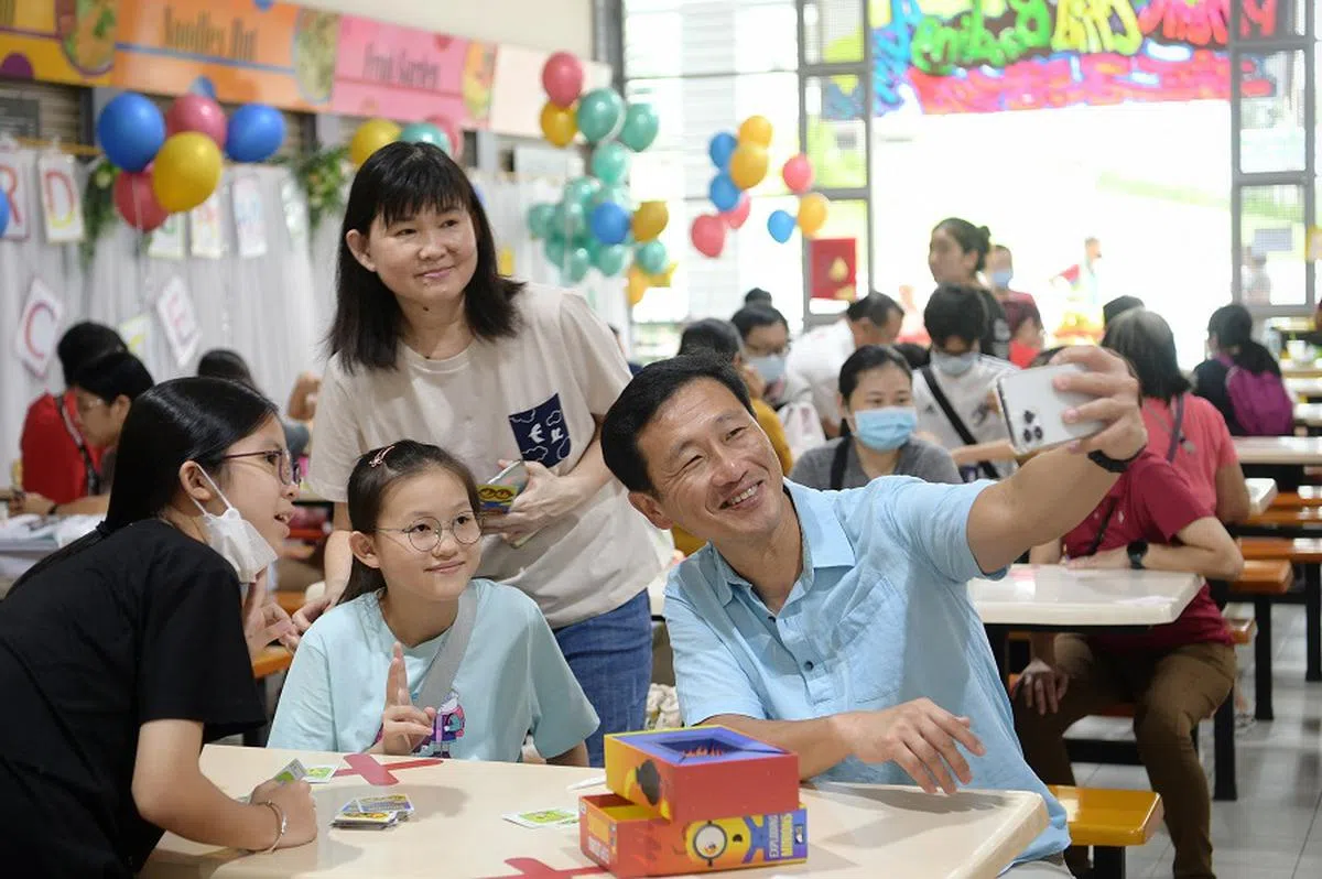 卫生部长王乙康（右一）出席华社自助理事会举办的“准备上学咯！”活动时与在场的学生与家长自拍。（海峡时报）
