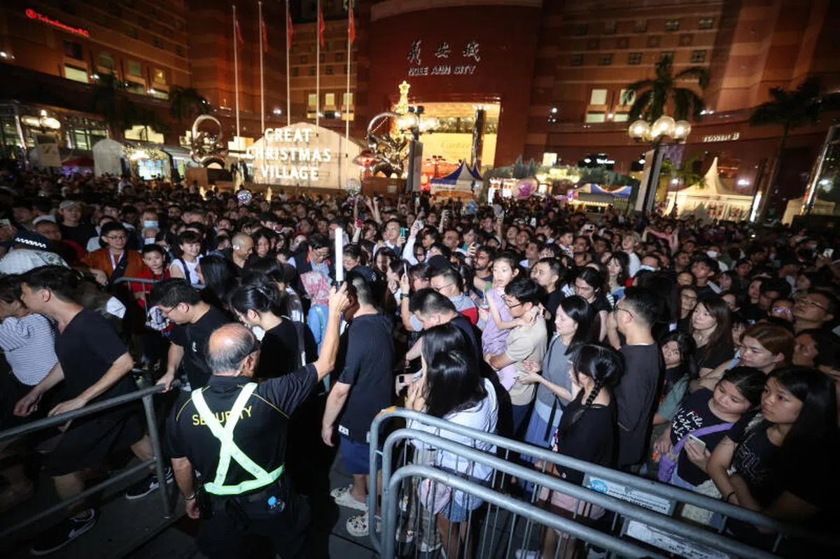 2024年平安夜，乌节路第二年封路举办大型圣诞派对，义安城前一片人头攒动、人潮川流不息。图中的保安员坚守自己的岗位。（联合早报）