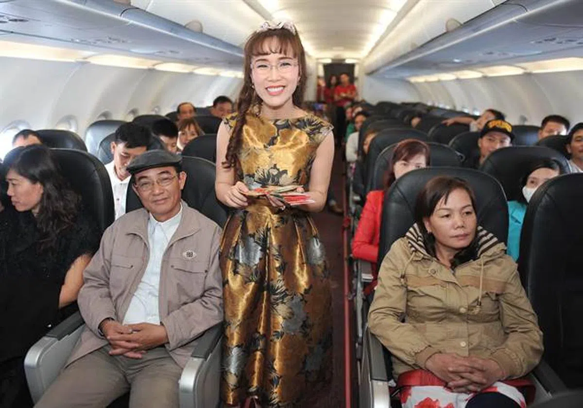  越南亿万女富豪，越捷航空执行长阮氏芳邵（中）与乘客同乐。（互联网） 