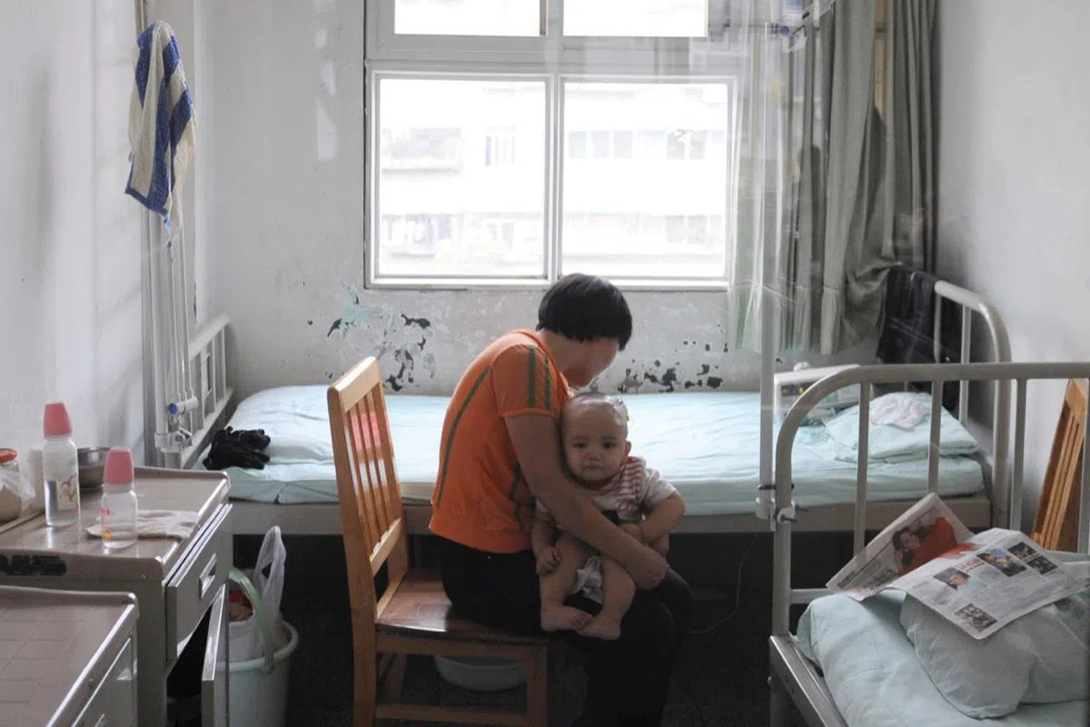  摄于成都儿童医院，一位母亲抱着受三聚氰胺污染奶粉影响而患上肾结石的婴儿。（Getty Image） 