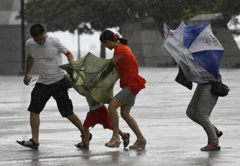 飓风山竹来袭时，香港街道上的行人寸步难移，手上有雨伞也根本排不上用场。（美联社）