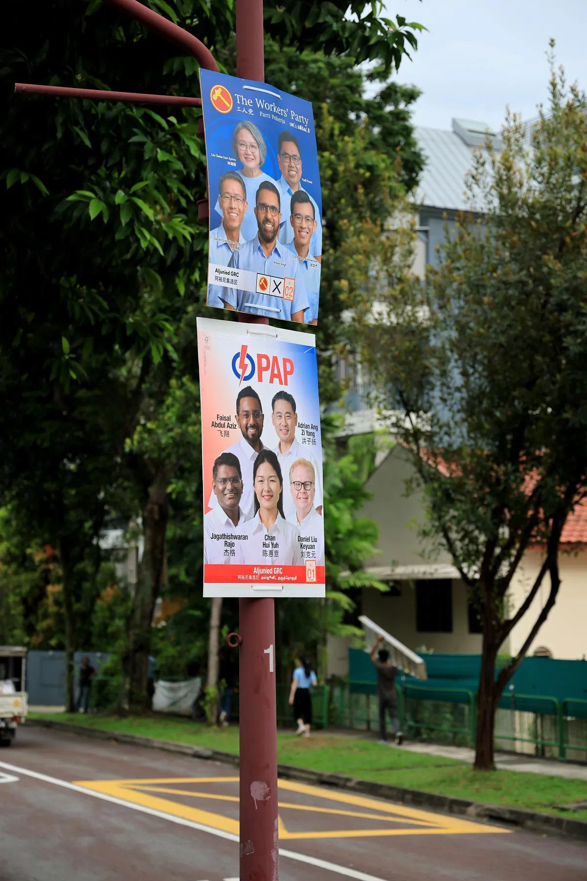 守土阿裕尼集选区的工人党团队和对手人民行动党团队贴在灯柱上的海报。（联合早报）