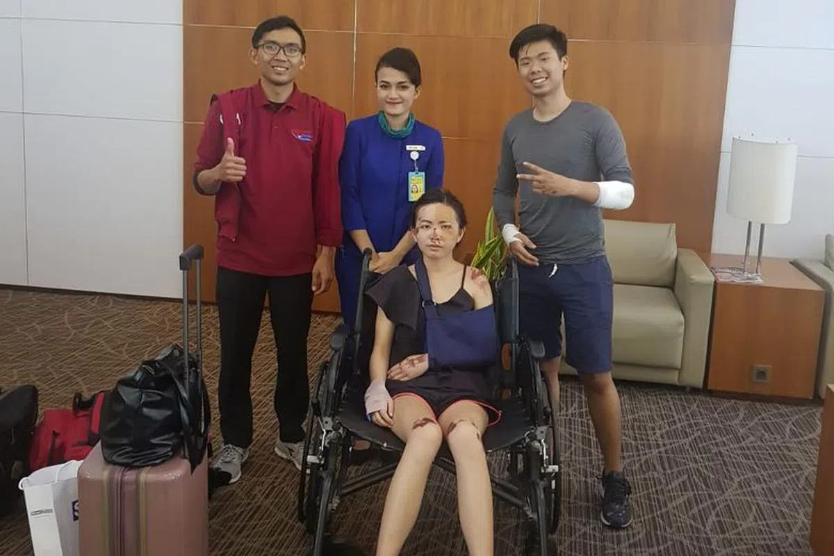  右一摆出“耶”手势的是丈夫，轮椅上面无表情的是受伤的妻子。（海峡时报） 