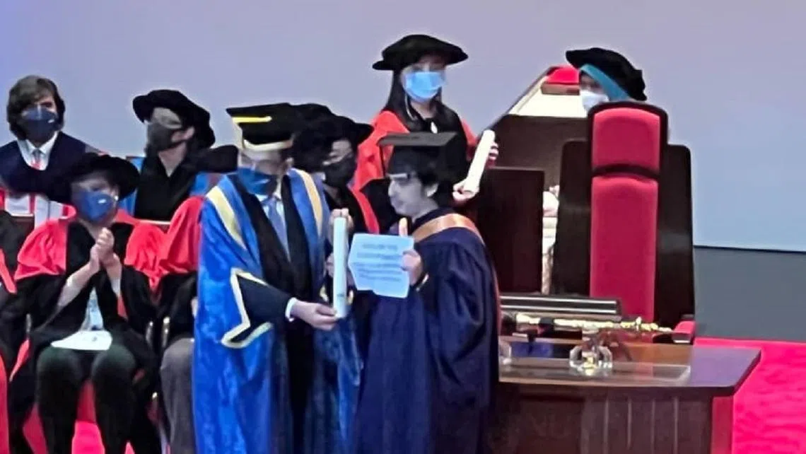 毕业生卢克（举纸张者）申诉国大在随后上传的毕业典礼视频中，剪掉了他上台的部分。（Luke Levy）