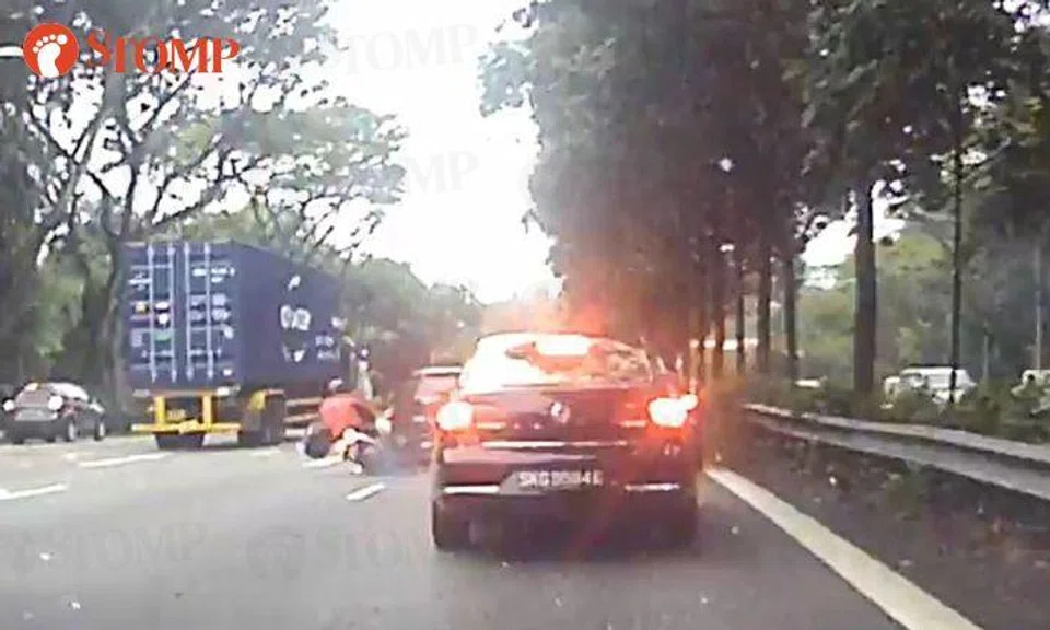 Biker skids on road after car changes lane along PIE