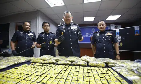 4 Malaysian policemen hold up the materials seized from a raid