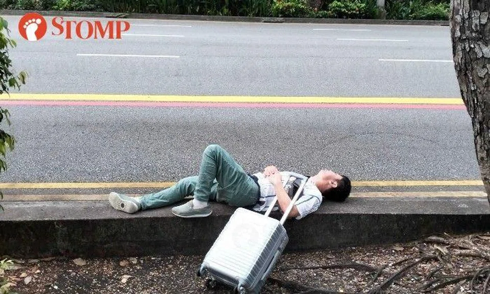 A photo shared by Stomper Nit Ray shows the man lying on his back next to the double yellow lines opposite the Voco Orchard Singapore hotel in front of Palais Renaissance.