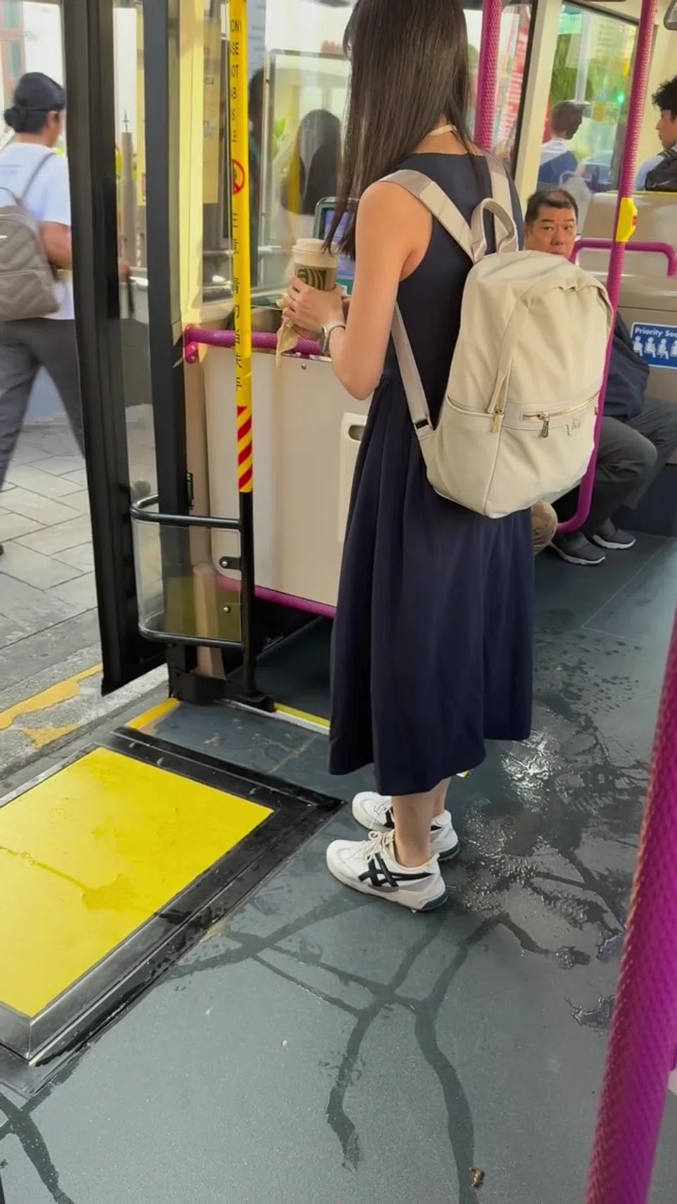 Woman's coffee spills on man's pants on bus, he pours water to clean it off