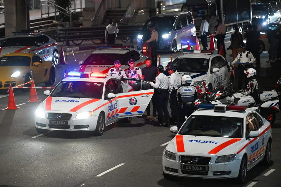 Traffic Police officers escorting a motorist suspected of drink driving to a patrol car during the Sept 20 operation in Upper Cross Street.