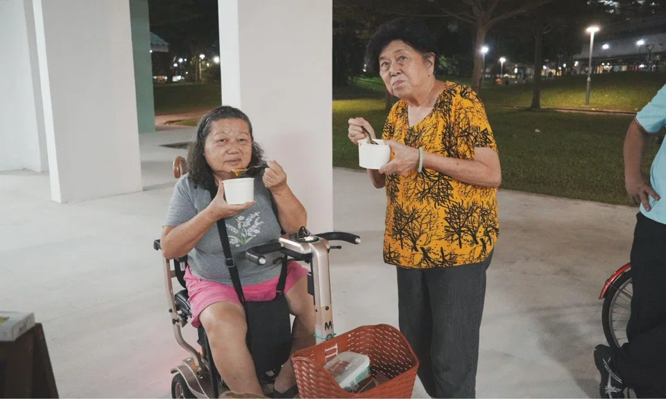 Two elderly women holding soup pose for a photo.