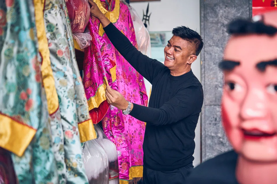 The chef-cum-performer inspects the intricate funeral costumes he wears as part of his role in traditional Chinese funeral rites.