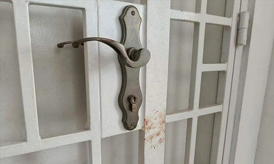 Bloodstains seen on the gate of the flat where the victims lived. The attacker, Abdul Karim V. Sickander, pleaded guilty to four charges on May 22, 2023. PHOTO: ST FILE
