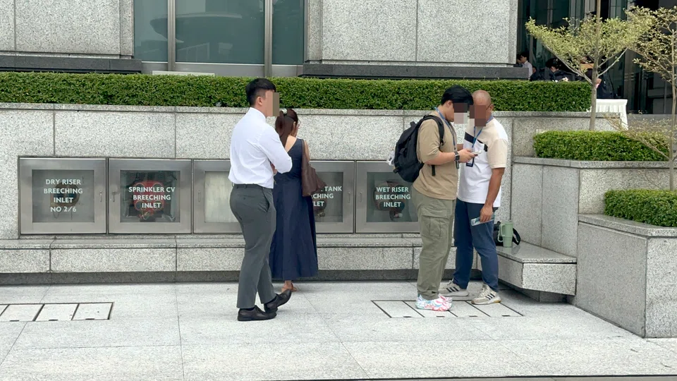 Two HSA officers (right) logging the details of a vape offender on Aug 20 at UOB Plaza. ST PHOTO: ZAIHAN MOHAMED YUSOF