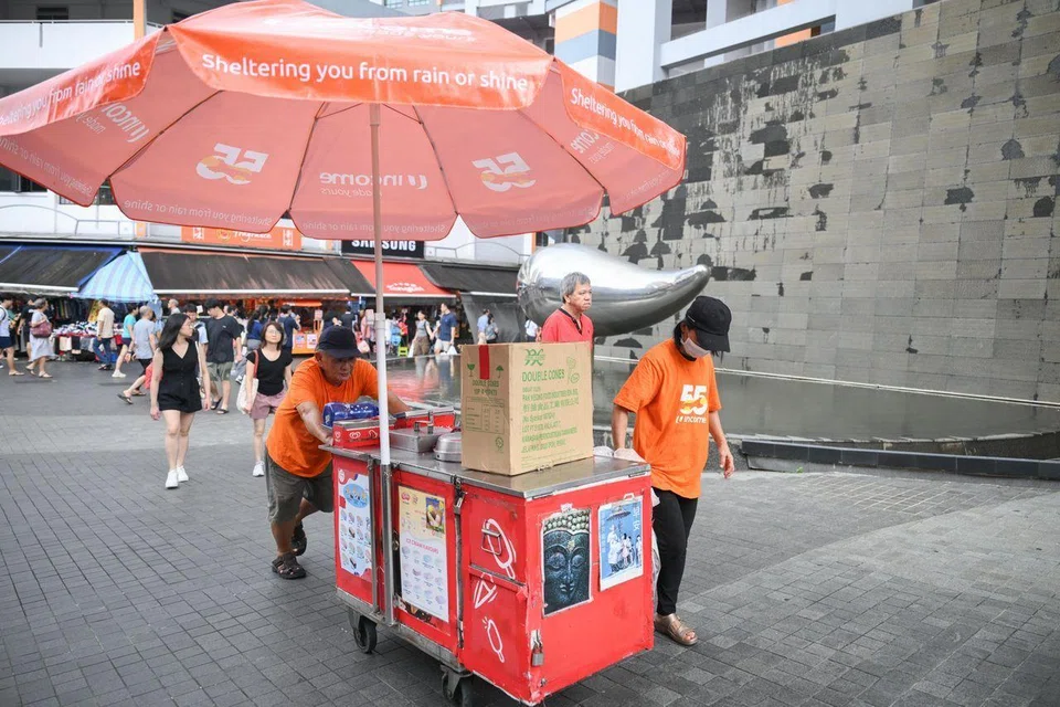 Mr Cheong moving his ice cream cart to a sheltered walkway due to the rain. ST PHOTO: SHINTARO TAY